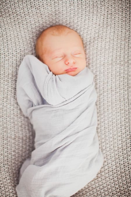 Baby schläft eingepuckt auf einer Decke