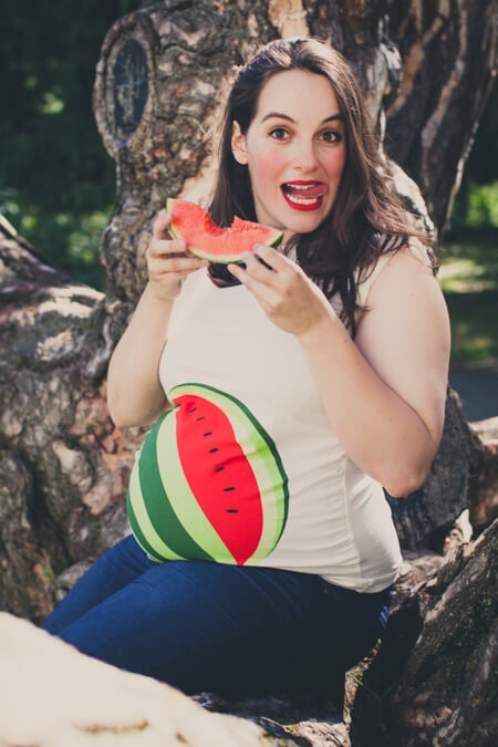 Frau mit Babybauch beißt in eine Melone