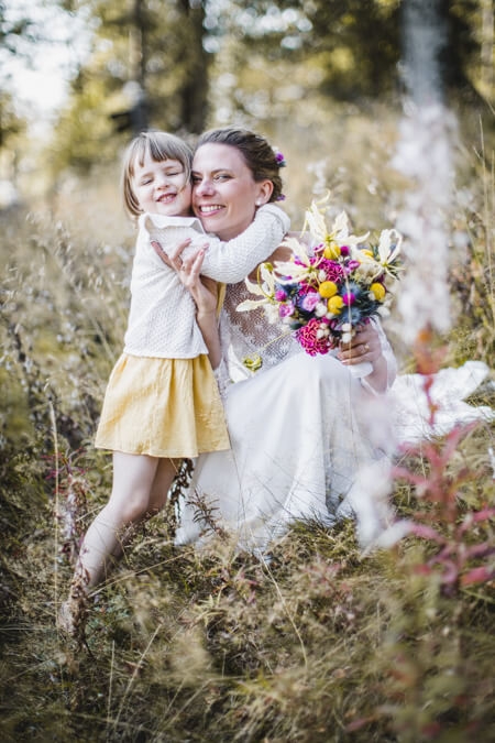 Braut wird von ihrer Tochter umarmt auf einer Wiese