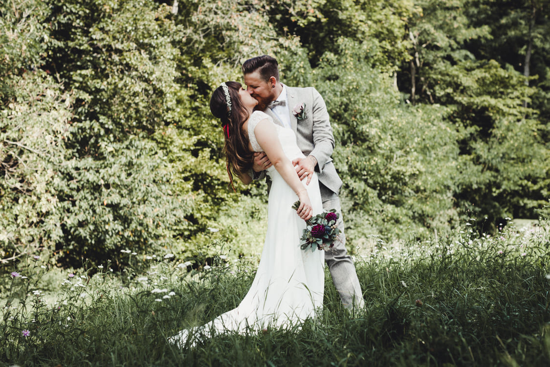Brautpaar küsst sich auf einer Wiese