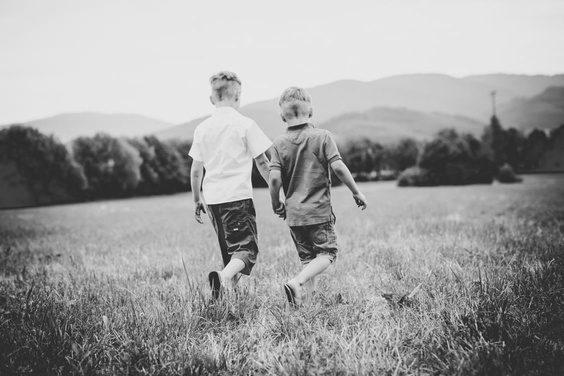 Brüder sind von hinten zu sehen wie sie über eine Wiese laufen