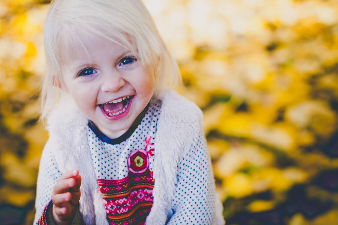 Lachendes Mädchen vor gelben Blättern