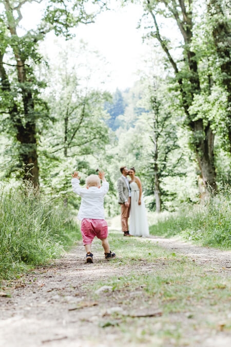 Kleiner Junge rennt auf seine Eltern das Brautpaar zu