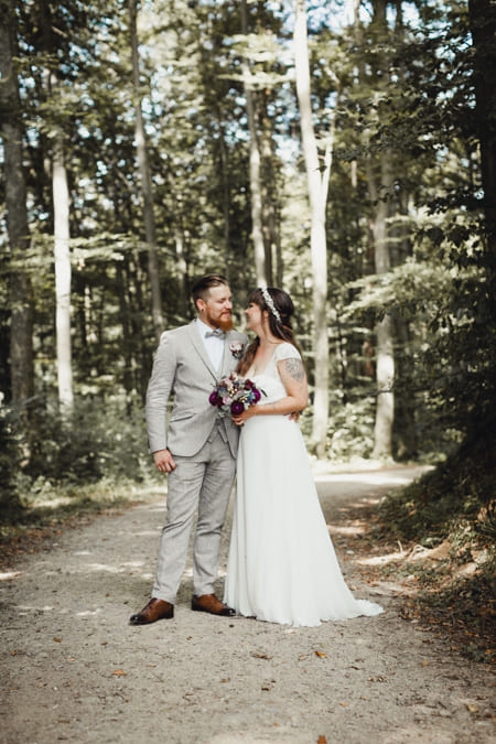 Brautpaar steht auf einem Waldweg und schaut sich an