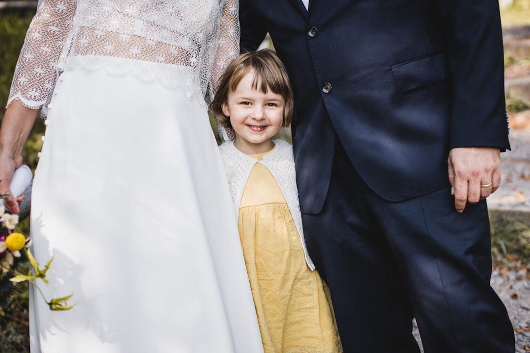 Kind schaut zwischen Braut und Bräutigam hervor