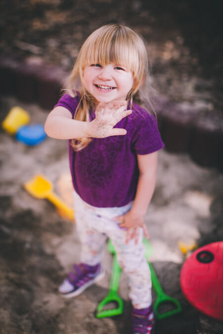 Mädchen steht im Sandkasten