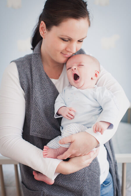 Baby gähnt bei Mama auf dem Arm