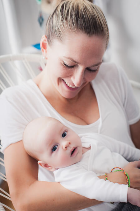 Mutter schaut ihr Baby an welches sie im Arm hält