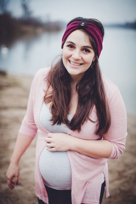 Schwangere Frau mit rosa Strickjacke und Stirnband im Winter