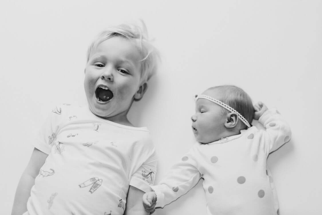 Junge liegt auf dem Batt neben seiner kleinen Schwester und schreit