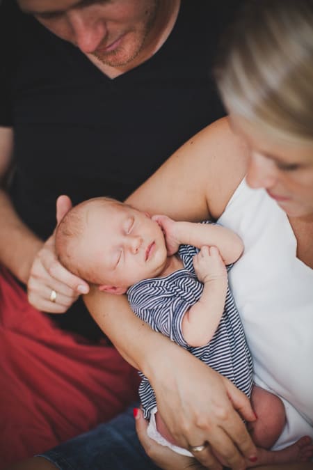 Baby schläft in den Armen der Eltern