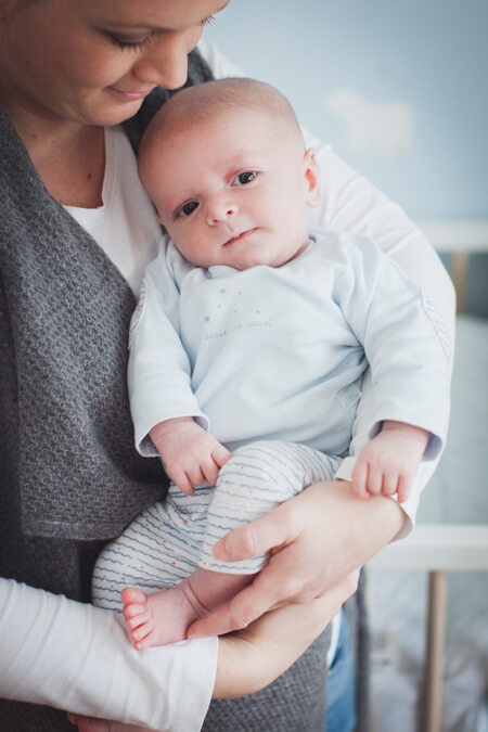 Baby lächelt  zufrieden bei Mama auf dem Arm