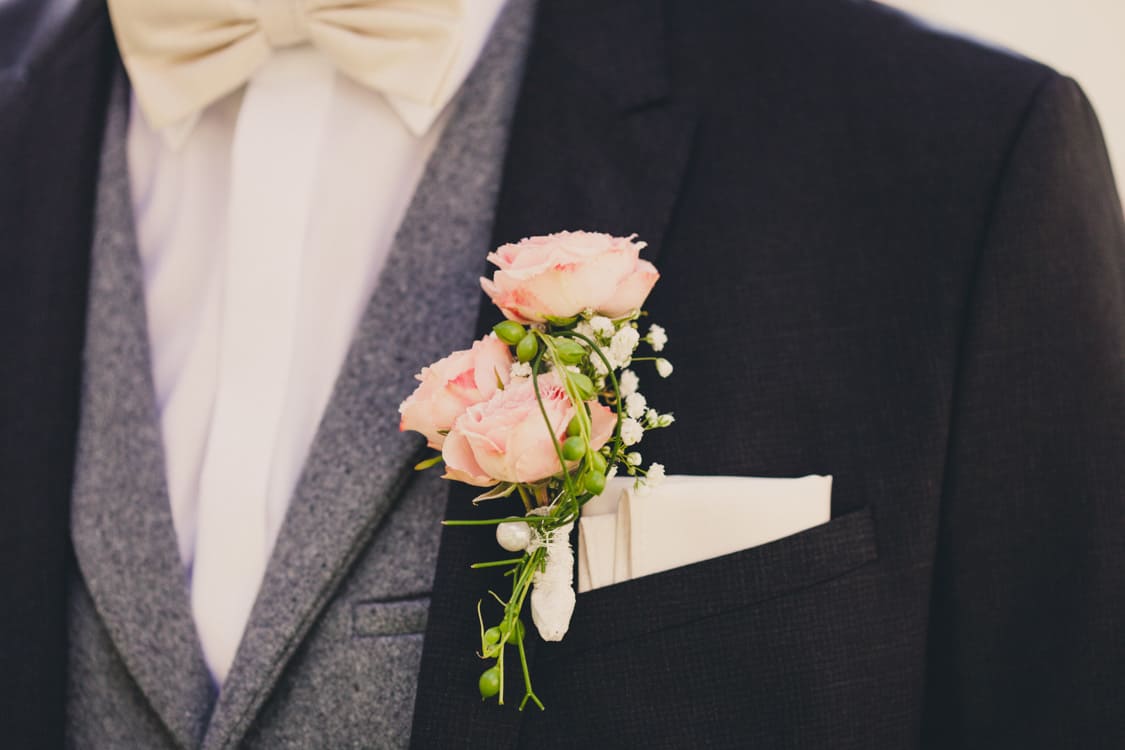 Nahaufnahme vom Einstecktuch und Blumenanstecker des Bräutigamms