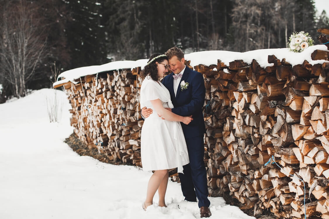 Brautpaar vor Holzscheit im Schnee