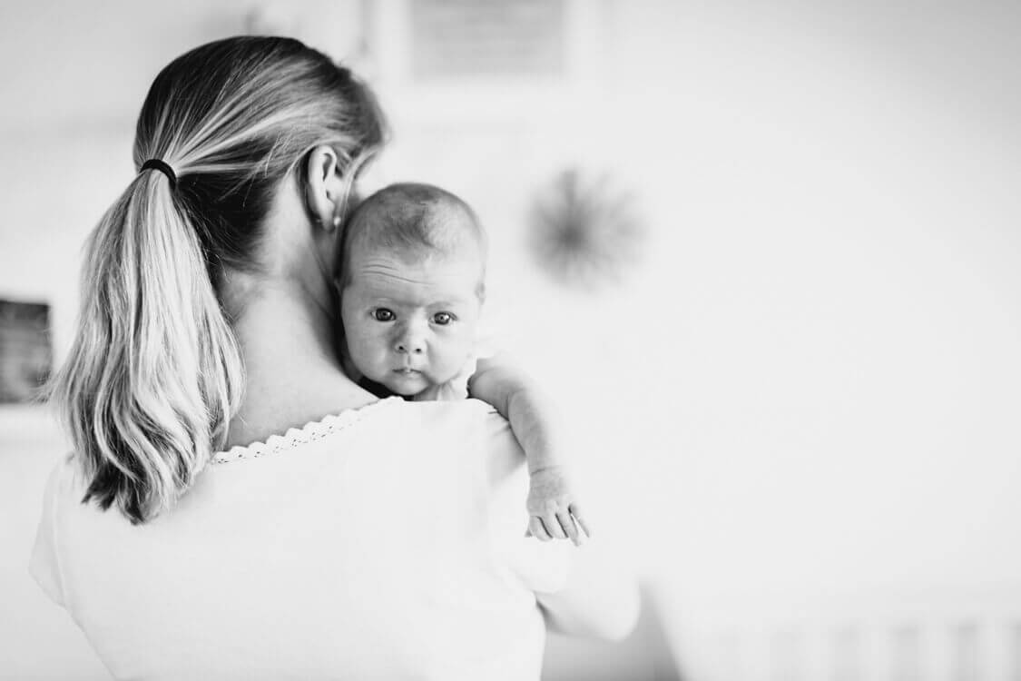 Mutter hält ihr Neugeborenes über die Schulter
