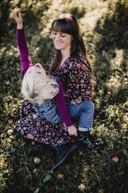 Foto von oben von Mutter mit Tochter auf dem Schoß. Das Mädchen streckt ihren Arm nach oben.