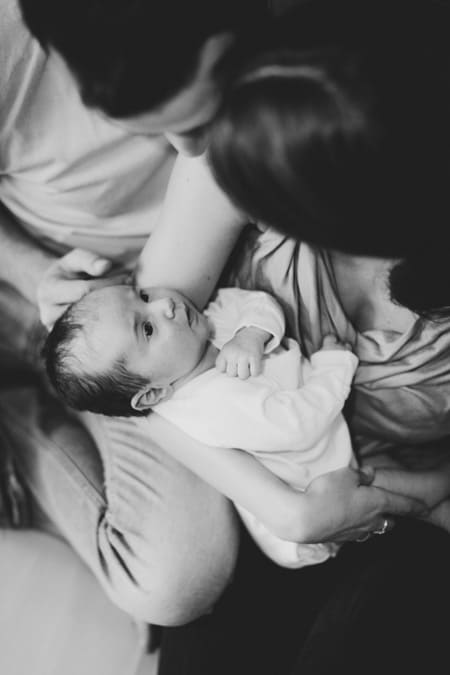 Eltern halten ihr Baby im Arm und schauen es an