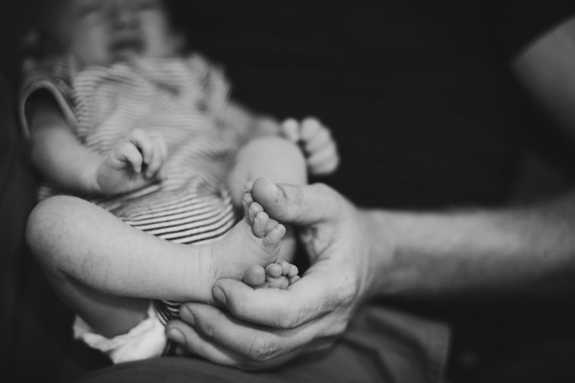 Babyfüße in der Hand des Vaters