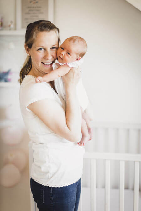 Mutter mit ihrem Baby auf dem Arm stehen im Kinderzimmer