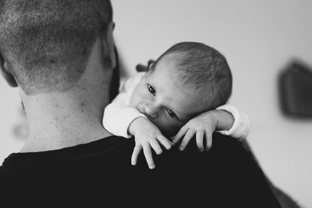 Neugeborenes hängt über der Schulter vom Vater