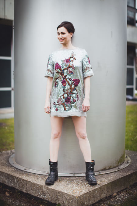 Frau mit Paillettenkleid steht vor einem Schornstein