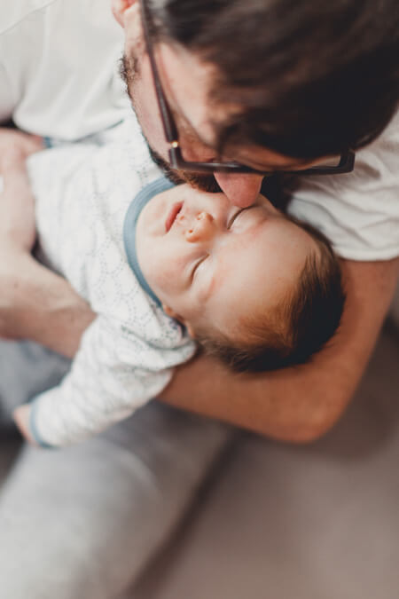 Vater hält seinen kleinen Sohn auf dem Arm. Blick von oben auf das schlafende Baby.
