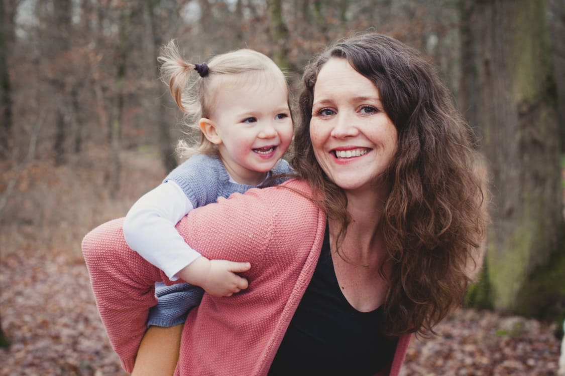 Kleines Mädchen sitzt Huckepack bei seiner Mama