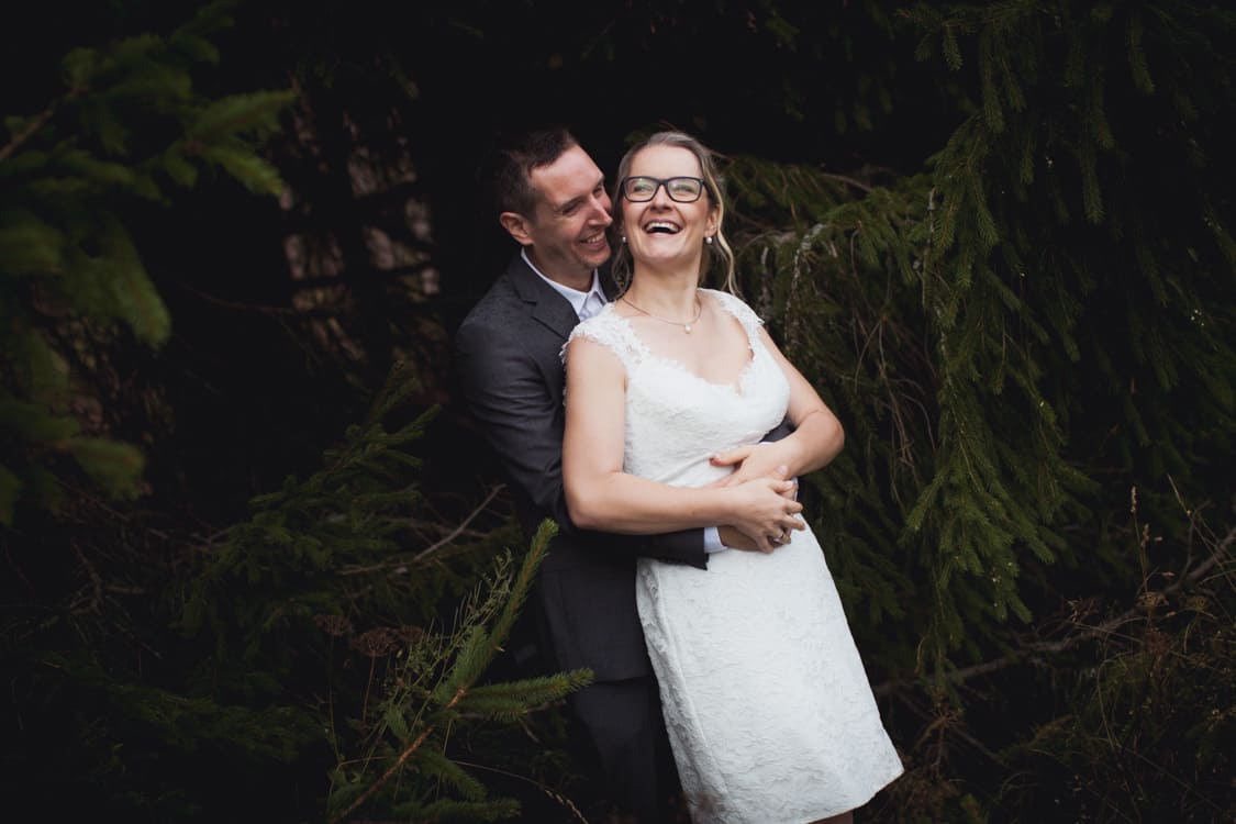 Brautpaar lachend vor einer Tanne