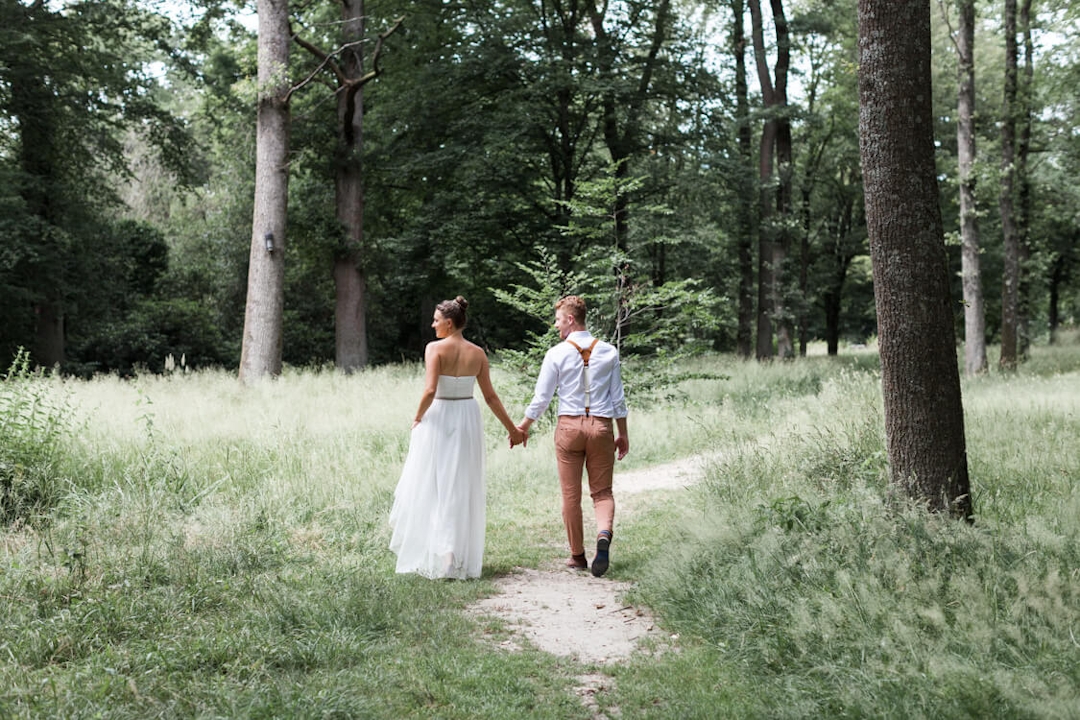 Brautpaar von hinten läuft durch einen Wald
