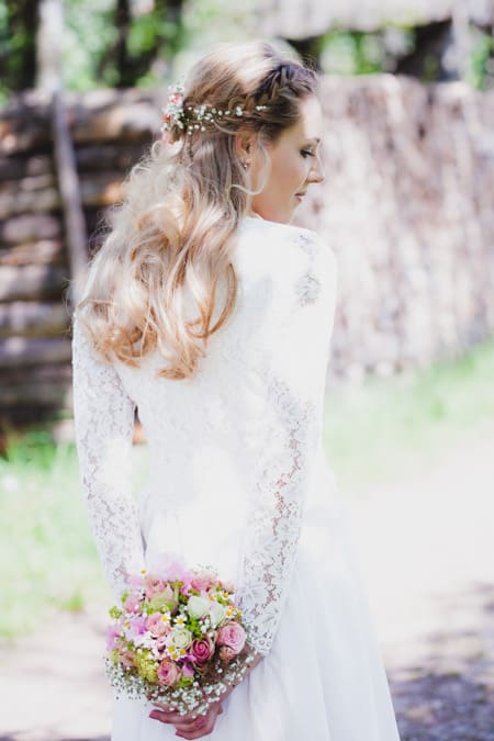 Braut hält Brautstrauß hinter dem Rücken