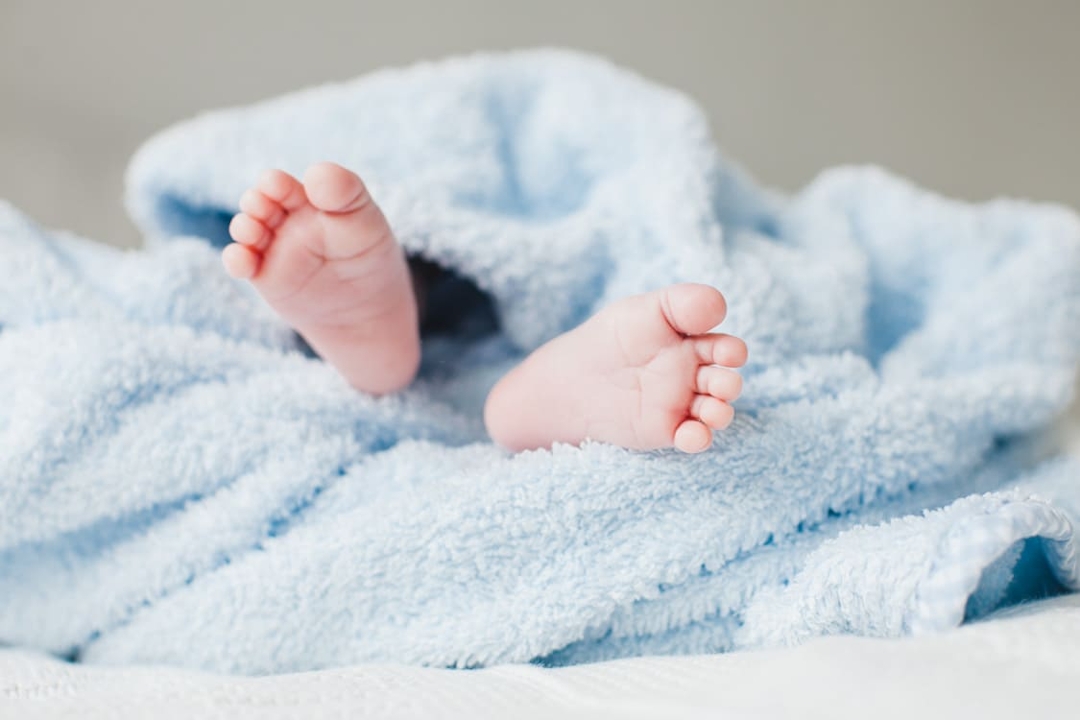 Babyfüße von baby welches in ein hellblaues Handtuch eingewickelt ist
