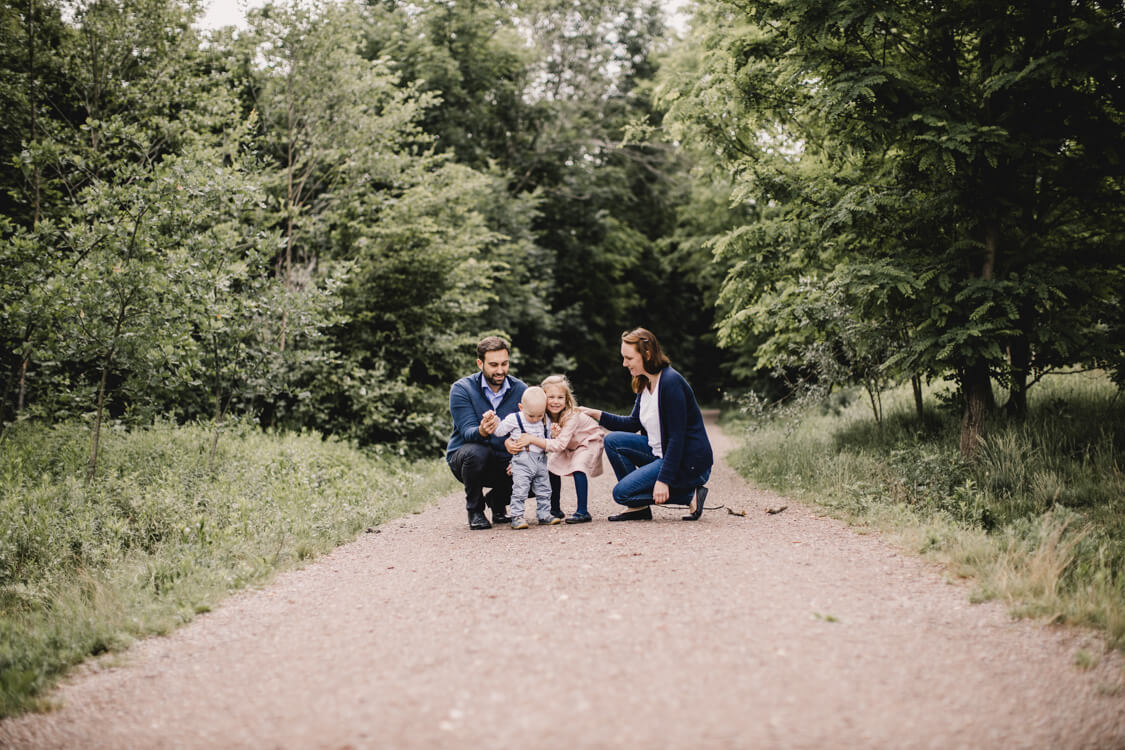 Familie sitzt in der Hocke auf einem Weg