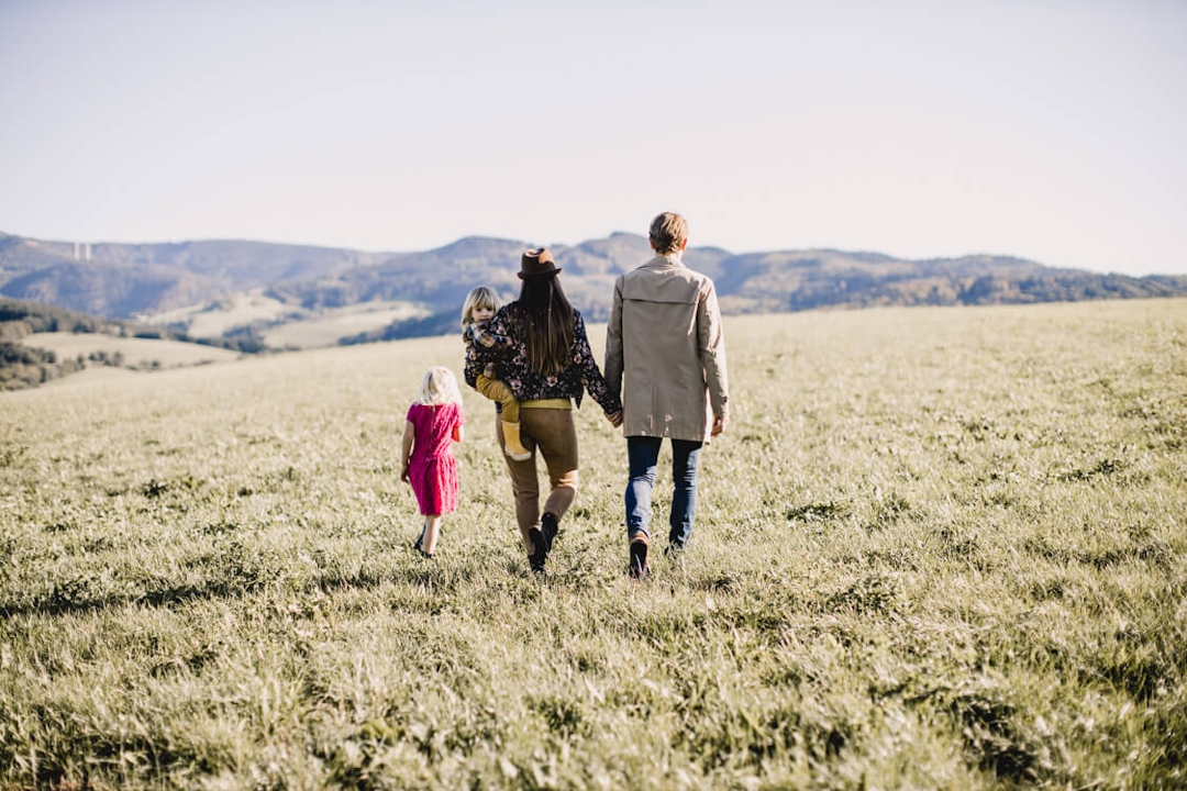 Familie mit zwei Kindern von hinten laufen über ein Feld